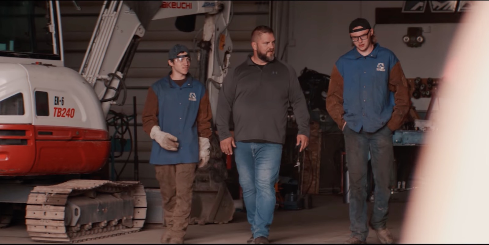 Adam Crum walking the shop floor with two apprentices at Northern Industrial Training, the trade school he helped build